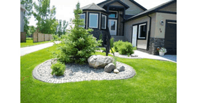 a house with a lush green lawn and a rock garden in front of it