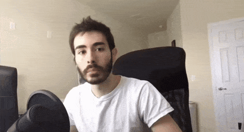 a man with a beard is sitting in a chair with a microphone in front of him