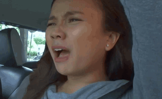 a woman is crying while sitting in a car