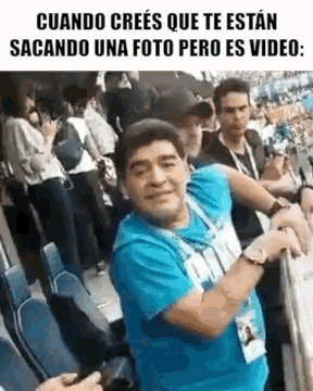 a man in a blue shirt is dancing in front of a crowd .