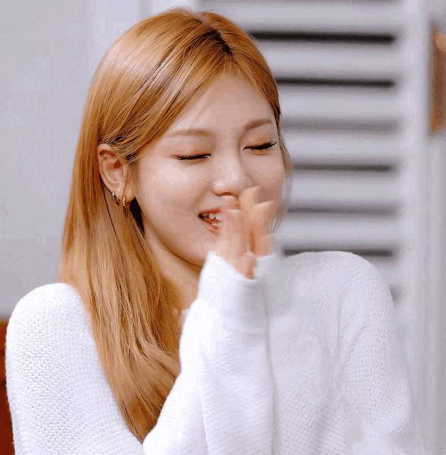 a woman covering her mouth with her hand and smiling