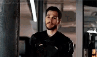 a man with a beard is standing in a room and looking at something .