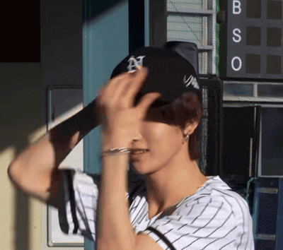 a baseball player adjusts his hat in front of a scoreboard that says bso