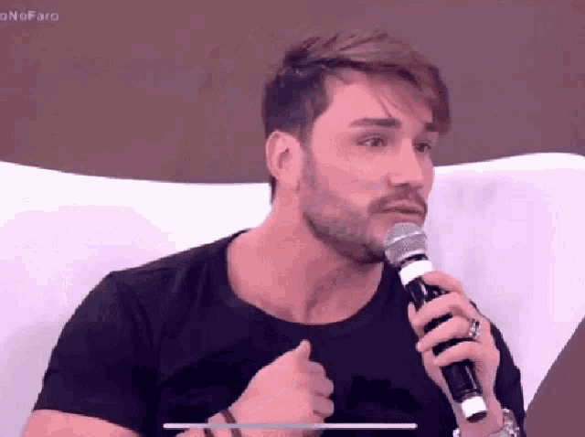 a man with a beard is holding a microphone in his right hand