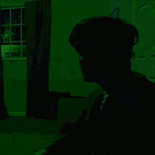 a man is sitting on a couch in a dark room with a blue light behind him