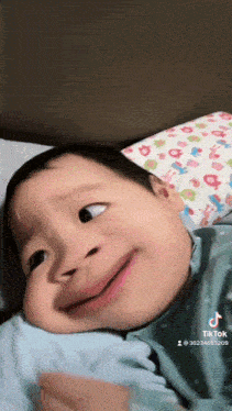a baby laying on a bed with a tiktok watermark on the bottom right