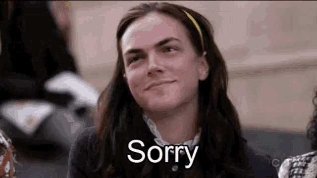 a woman is smiling and saying sorry while sitting down .