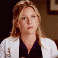 a close up of a woman wearing a white lab coat and purple scrubs .