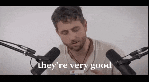 a man with a beard is sitting in front of two microphones and saying they 're very good .