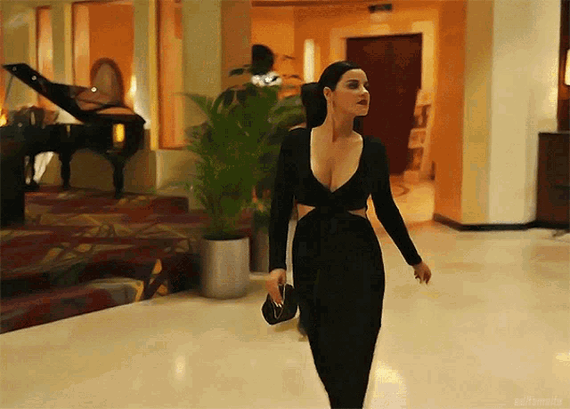a woman in a black dress walks through a hallway
