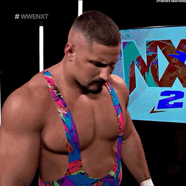a man in a colorful outfit is standing in front of a screen that says nx2