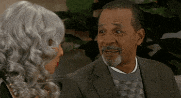 a man in a suit and a woman in a wig are talking to each other