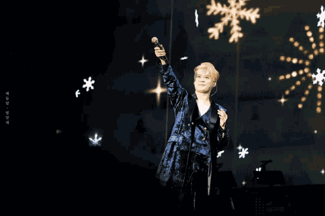 a man singing into a microphone in front of snowflakes and stars