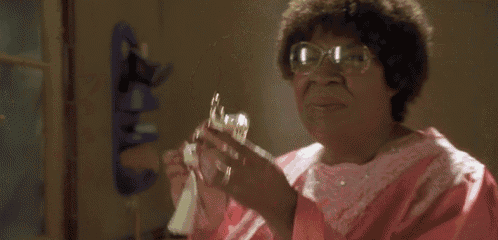 a woman in a pink dress holds a bottle of perfume
