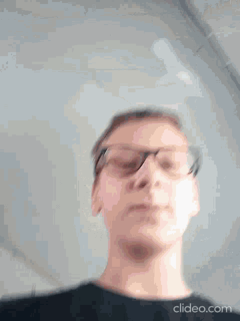 a blurry photo of a man wearing glasses and a black shirt .