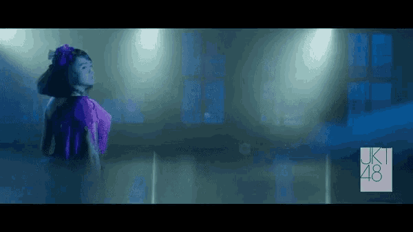 a girl in a purple dress is dancing in front of a sign that says uki 48