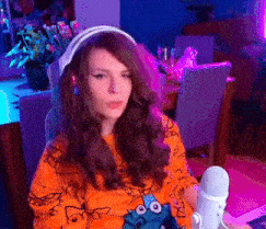 a woman wearing headphones is sitting in front of a microphone in a room .