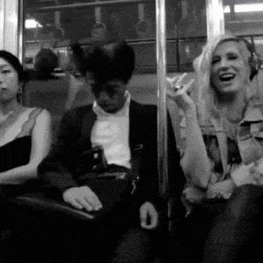 a woman wearing headphones laughs while sitting next to a man