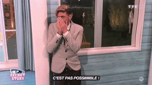 a man in a suit is standing in front of a window and covering his mouth with his hands while watching the secret story
