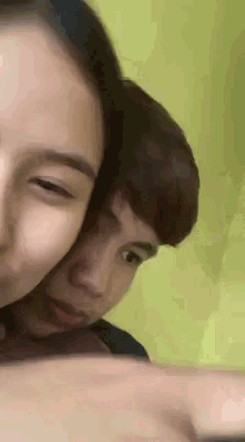 a man and a woman are hugging each other while looking at a cell phone .