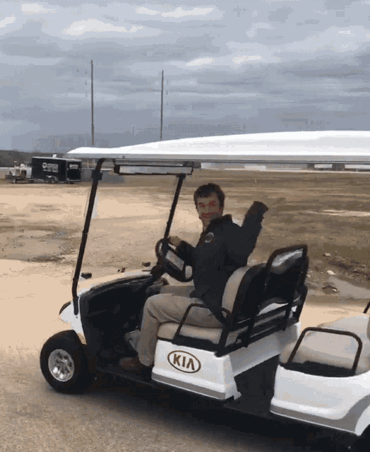 a man sits in a kia golf cart