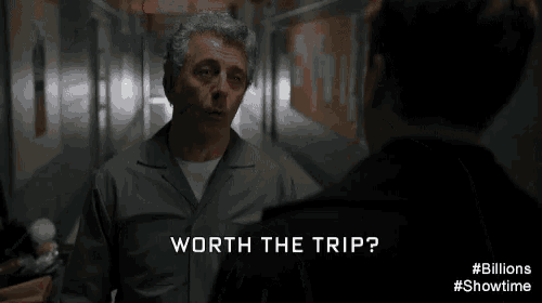 a man is talking to another man in a hallway and the man is saying yeah , worth the trip .