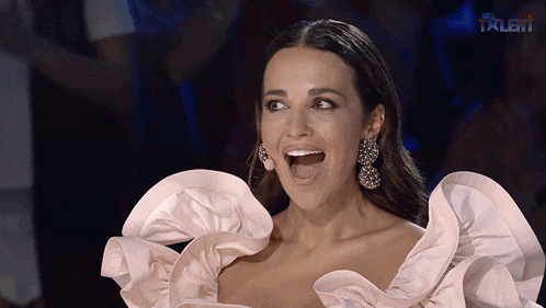 a woman in a pink dress with ruffled sleeves is smiling with the word talent on the bottom right