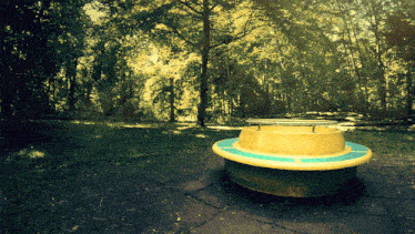 a yellow and blue picnic table in a park with trees in the background