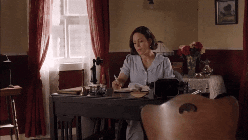 a woman sits at a desk with a pen in her hand