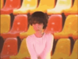 a blurry picture of a girl standing in front of a row of orange and yellow chairs