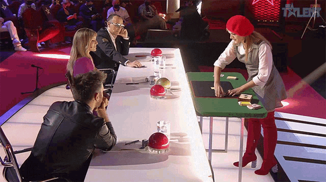 a woman in a red beret stands in front of a table with the word talent on the bottom right