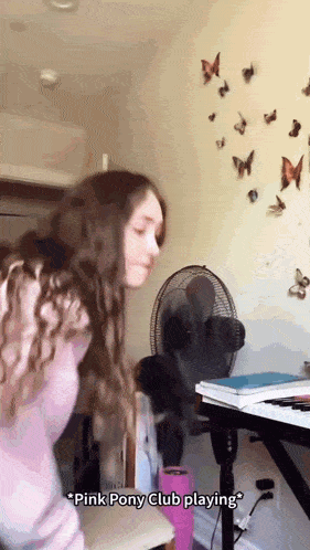 a girl standing in front of a fan with the words " pink pony club playing " written on the bottom