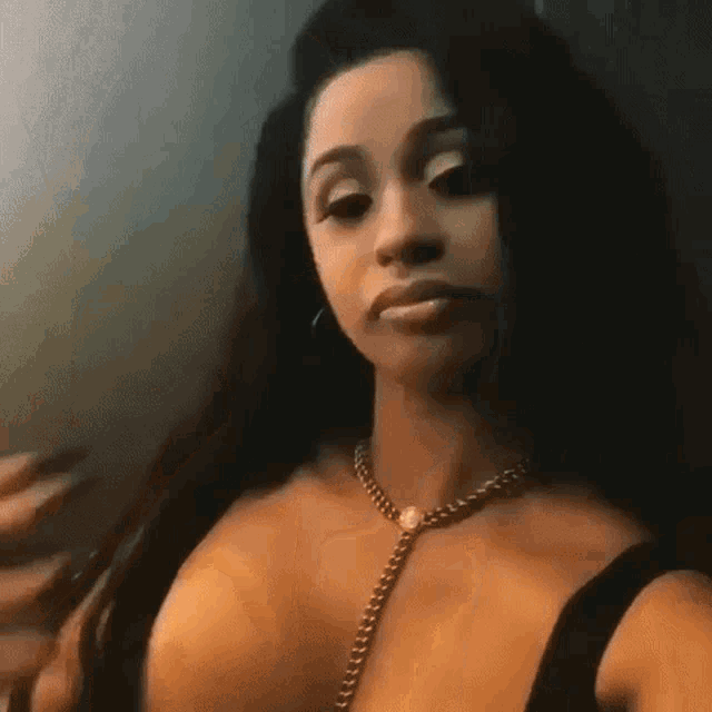 a woman is taking a selfie with her phone and wearing a necklace .