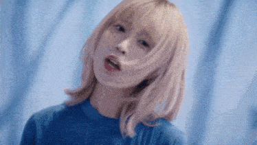 a woman with blonde hair and a blue shirt is looking at the camera