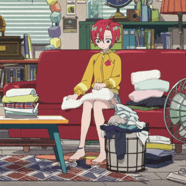 a girl with red hair is sitting on a red couch in a messy room