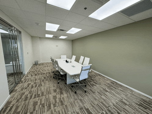 a conference room with white chairs and a long white table