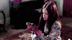 a little girl sitting on the floor holding a bird