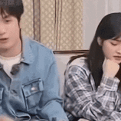 a man and a woman are sitting on a couch looking at each other .