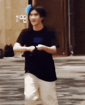 a man in a black shirt and white pants is standing on a carpet .