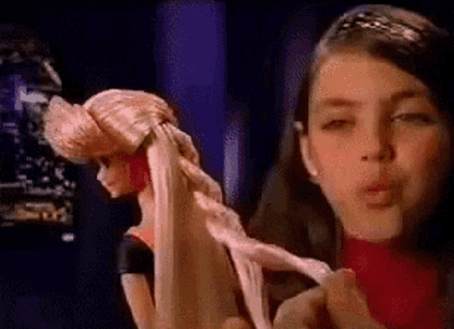 two girls are playing with a barbie doll in a video