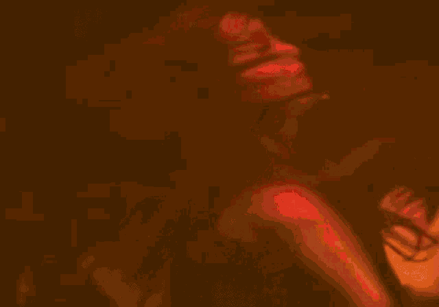 a woman is singing into a microphone in a dark room while another woman looks on .