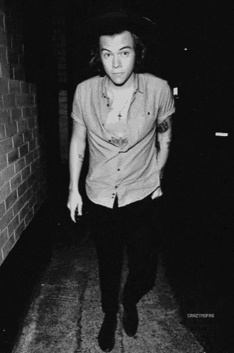 a black and white photo of a man with a tattoo on his chest and a necklace with a cross on it