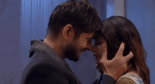 a man and a woman are kissing in a room .