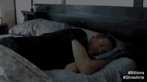 a man in a black shirt is laying in a bed with chinese writing on the bottom .