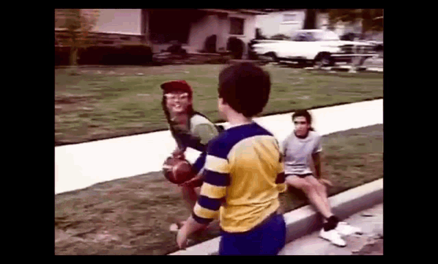 a group of young boys are playing basketball on a sidewalk .