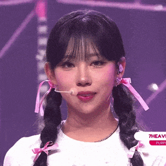 a girl with pigtails is wearing a white shirt and a microphone in her mouth ..