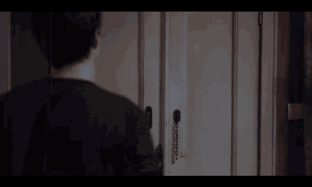 a man in a black shirt is standing in front of a door