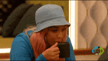 a woman with pink hair wearing a bucket hat drinking from a cup