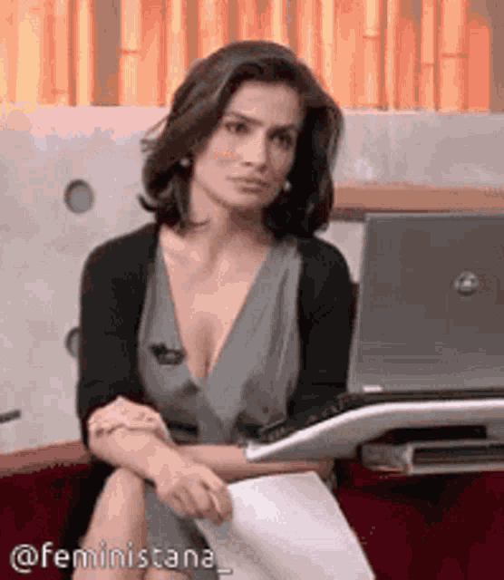 a woman is sitting in front of a laptop with the hashtag feministana at the bottom