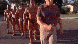 a group of muscular men are walking down the street